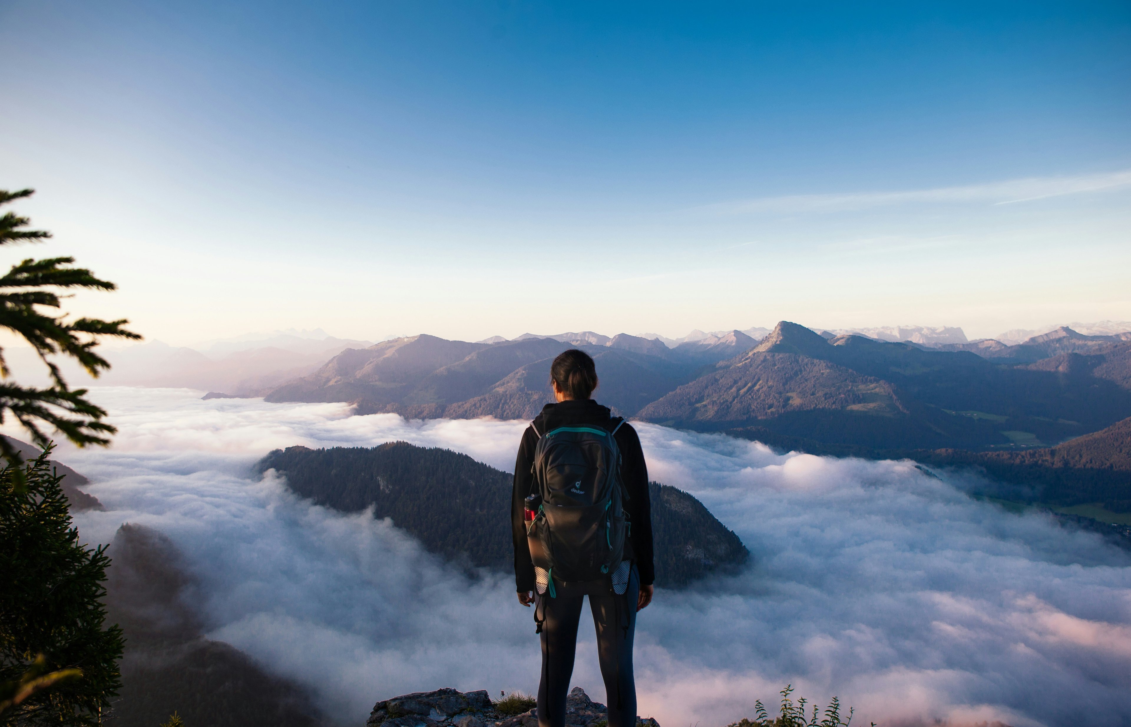 Person standing above the clouds on a mountain summit